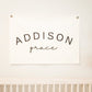 Custom canvas baby name banner with Addison Grace text hanging above wooden crib as nursery decor