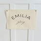 Custom canvas baby name banner by Little Joy Co. with the name Emilia Gray in black text on a cream canvas