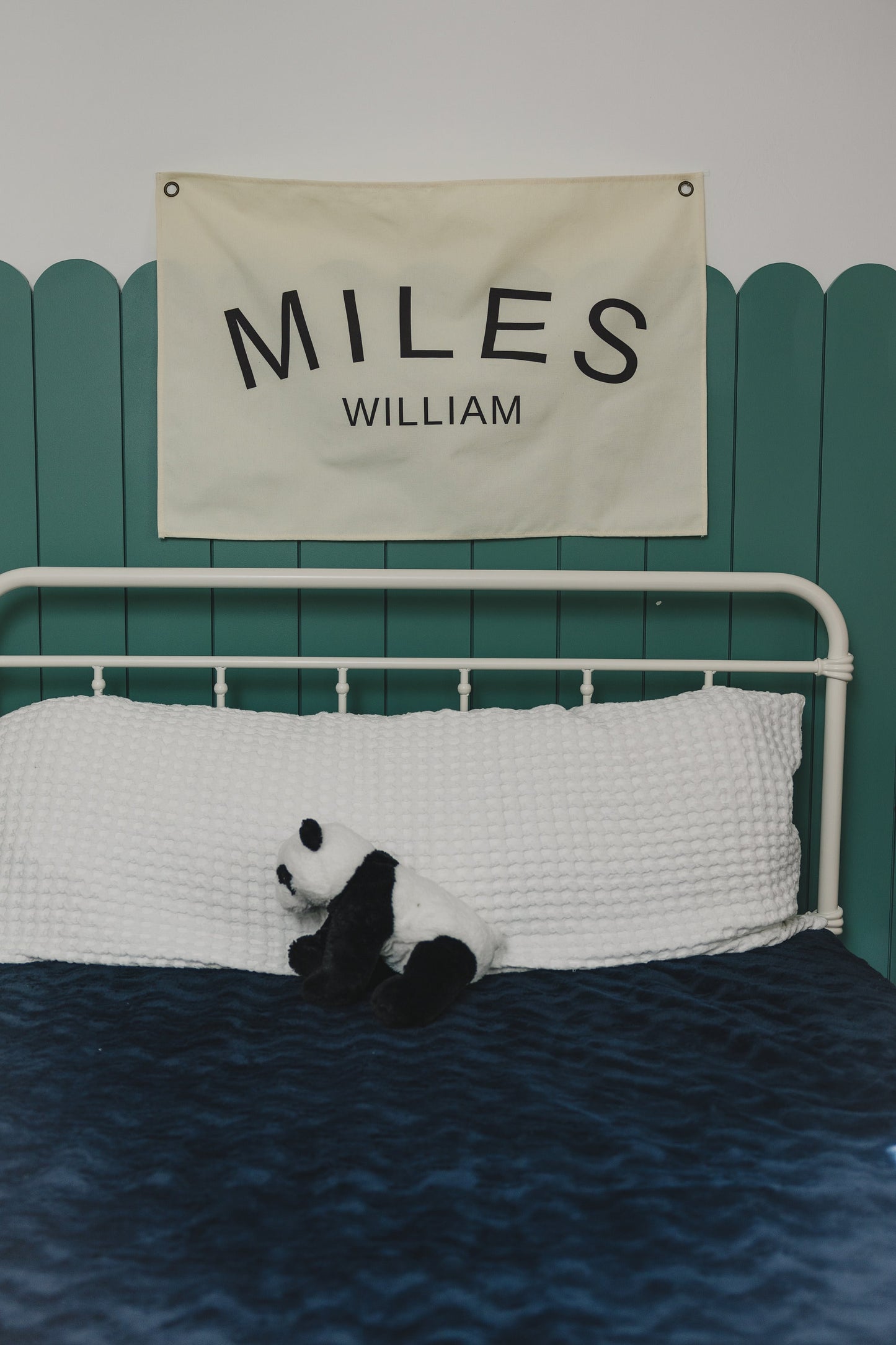 Custom canvas baby name banner with the name Miles William hanging above a white bed with a stuffed panda
