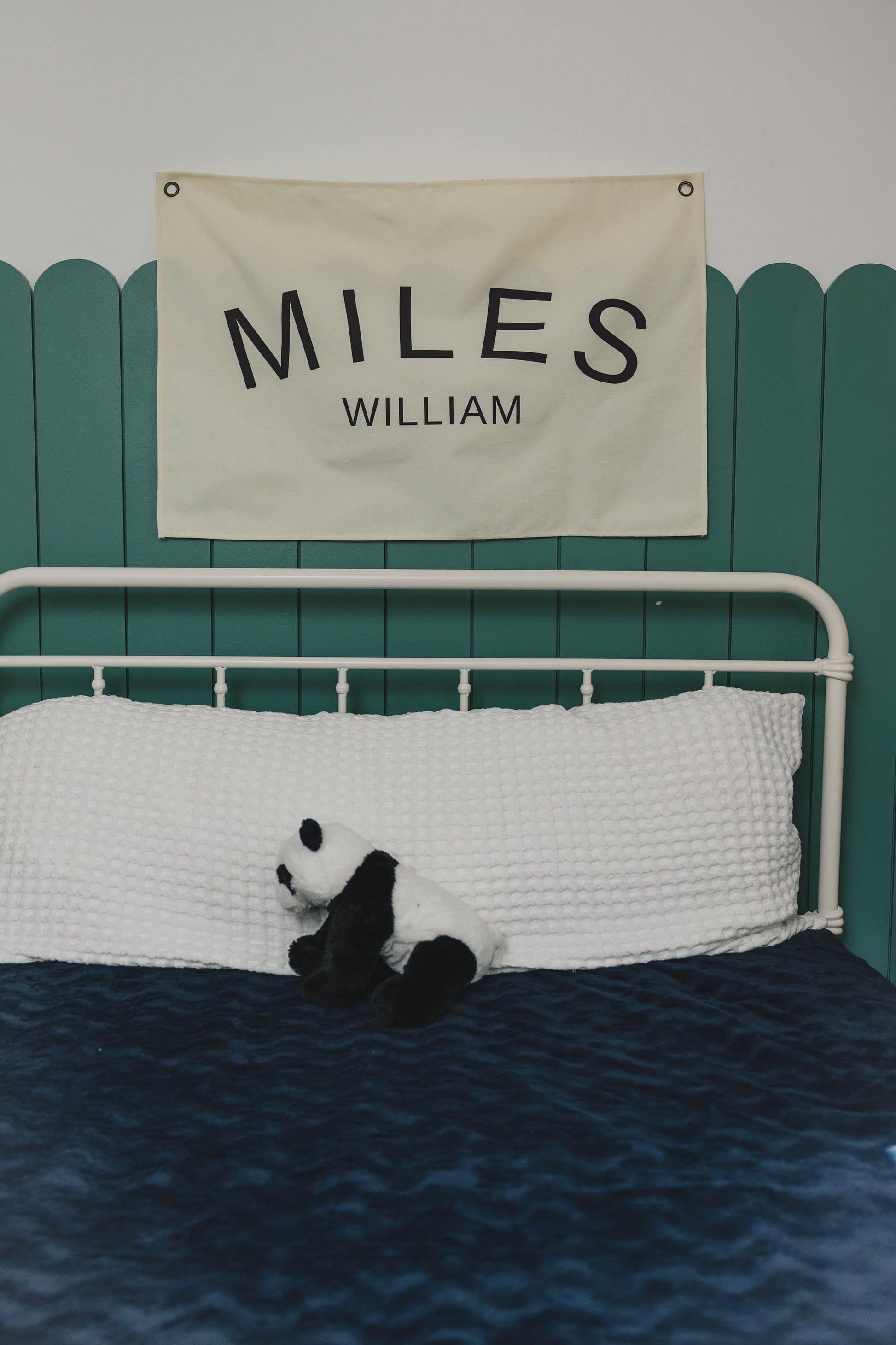 Custom canvas baby name banner with the name Miles William hanging above a white bed with a stuffed panda