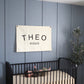 Custom canvas baby name banner with the name Theo Riggs hanging above black crib in nursery, alternate view
