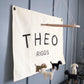 Little Joy Co. custom canvas baby name banner with the name Theo Riggs hanging on gray wall