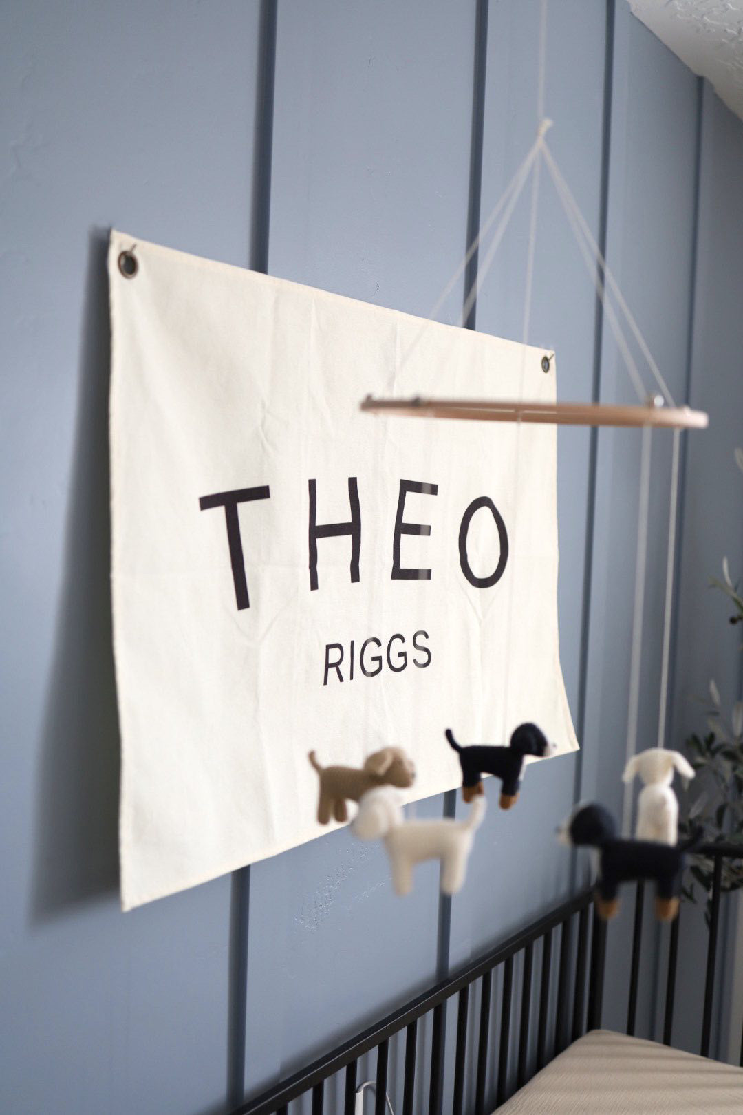 Little Joy Co. custom canvas baby name banner with the name Theo Riggs hanging on gray wall