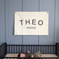Custom canvas baby name banner with the name Theo Riggs hanging above a black crib